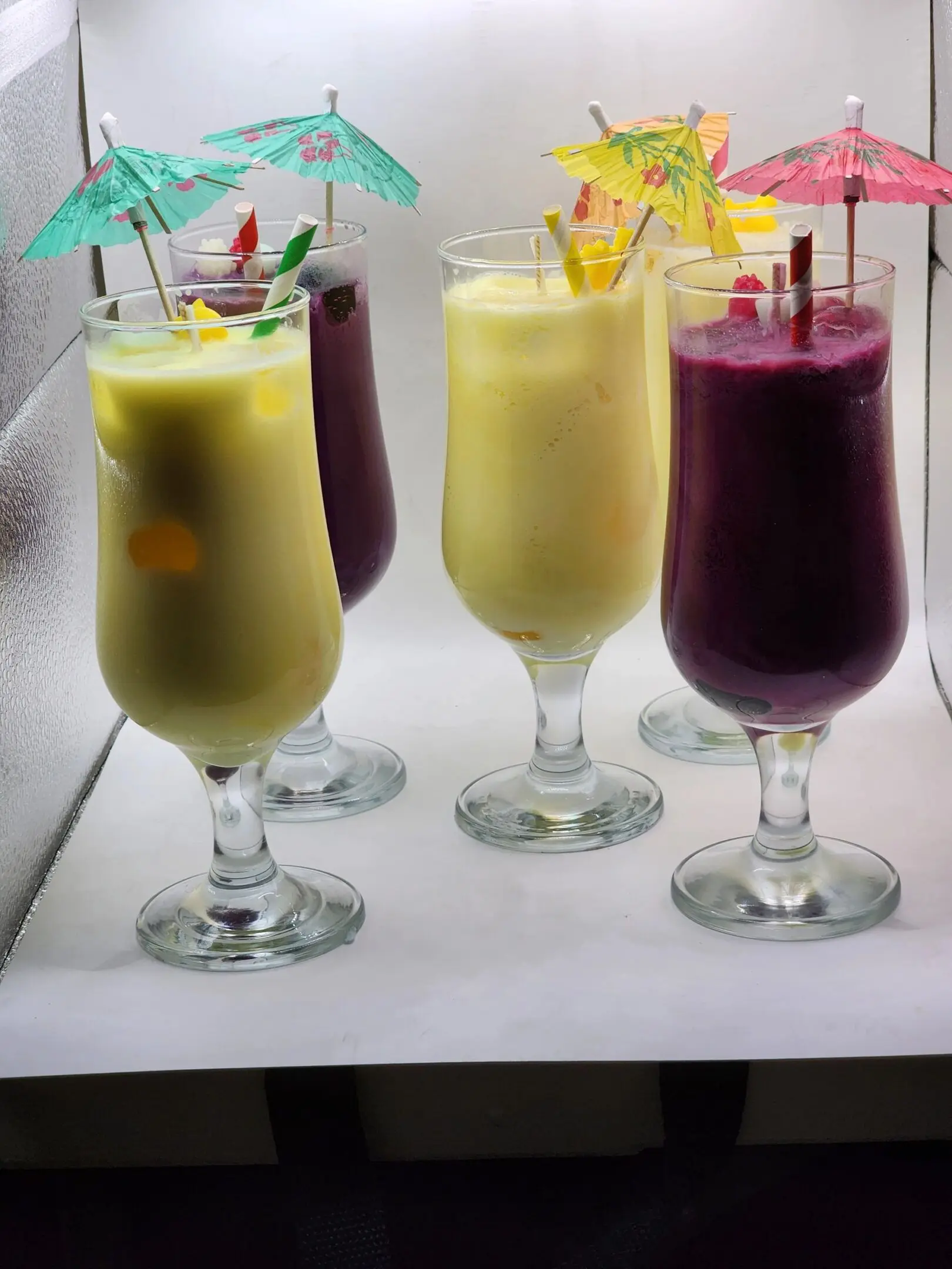 A group of four glasses filled with different drinks.