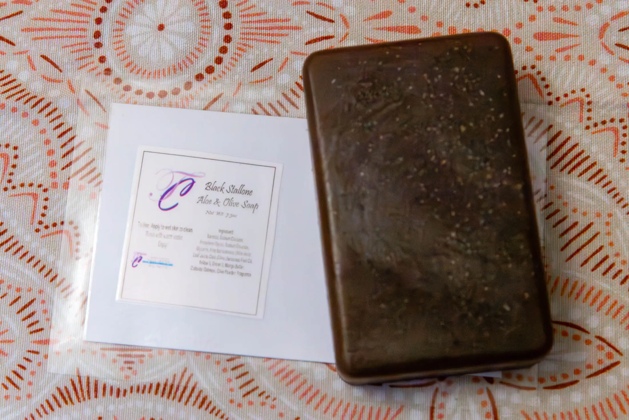 Chocolate bar and card on patterned tablecloth.