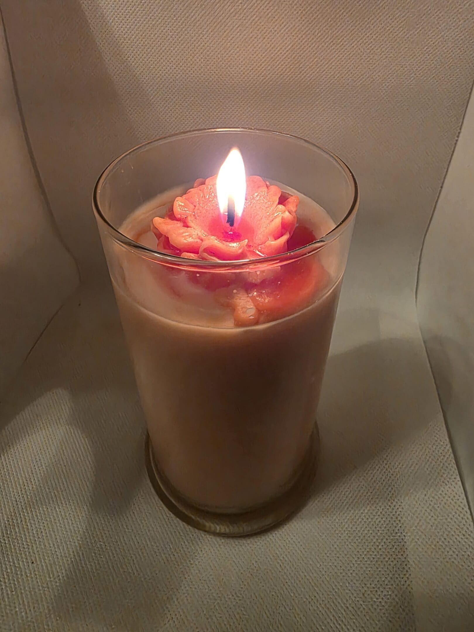 Lit candle with red rose design inside.
