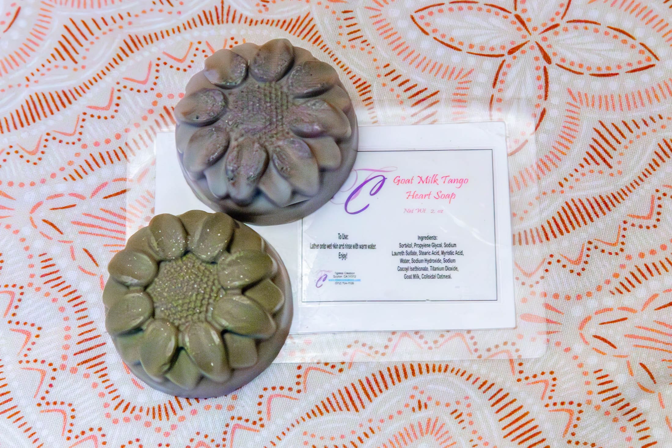 Two floral-shaped soaps on patterned fabric.